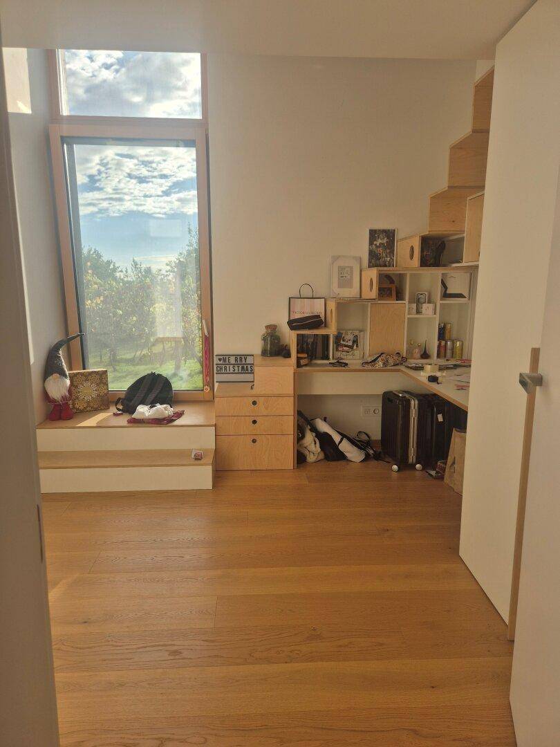 Heller Arbeitsbereich mit großem Fenster, Sitzbank und Blick auf die Landschaft.