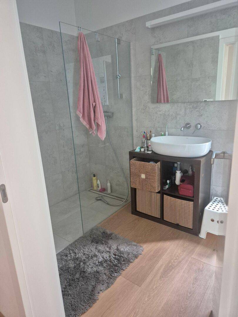 Modernes Badezimmer mit begehbarer Dusche, Einzelwaschbecken und Holzboden.