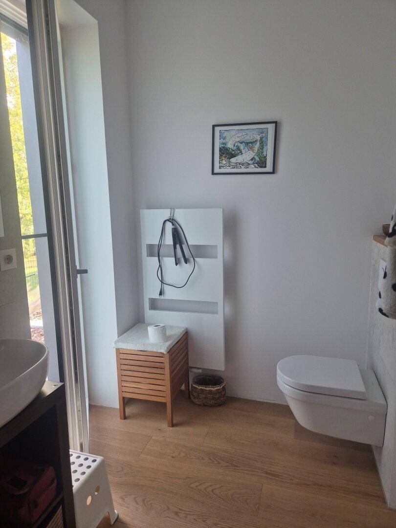 Badezimmer mit wandhängendem WC, beheiztem Handtuchhalter und Fenster.