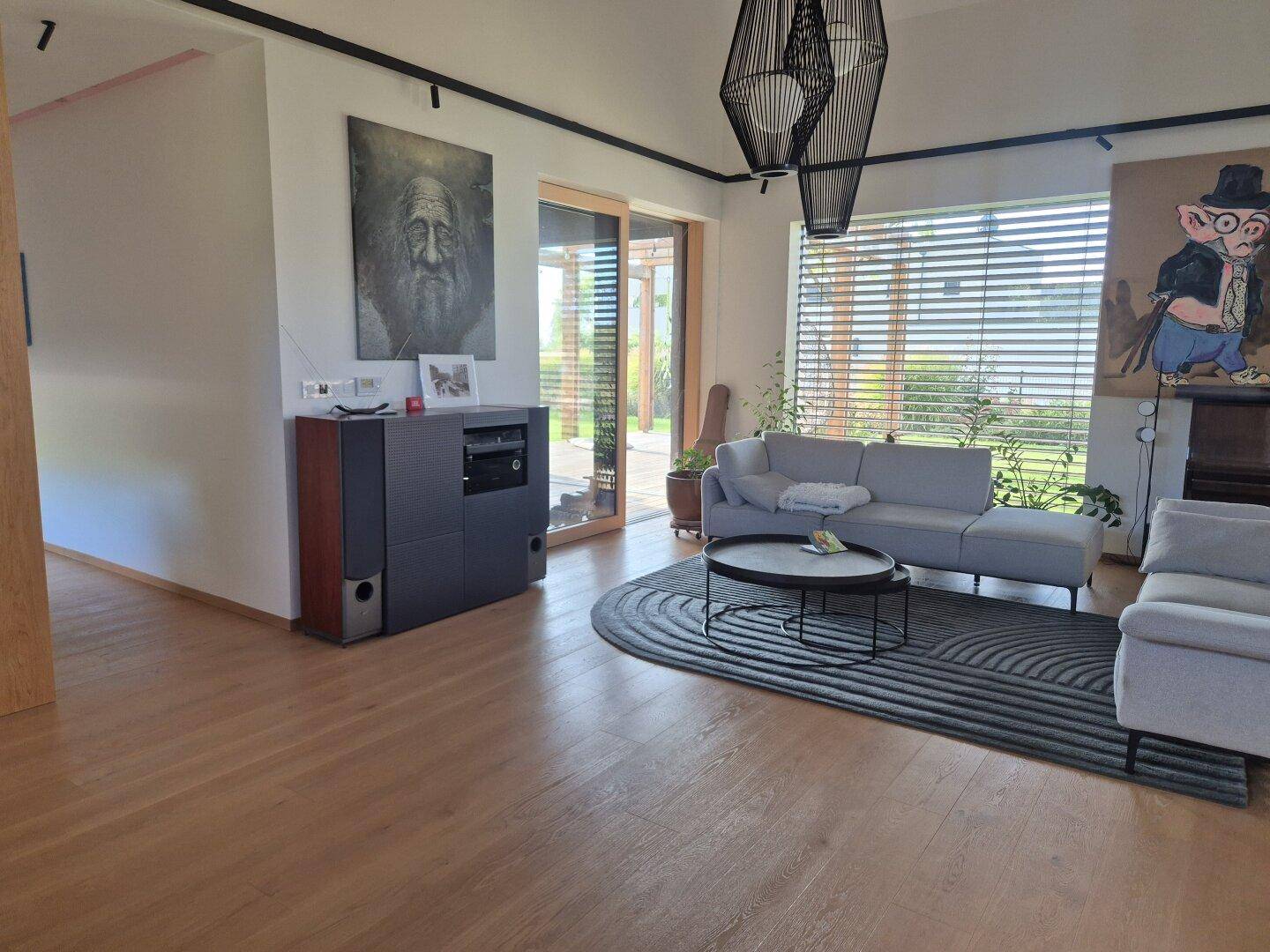 Wohnzimmer mit Holzboden, bequemen Sofas und großer Schiebetür zur Terrasse.