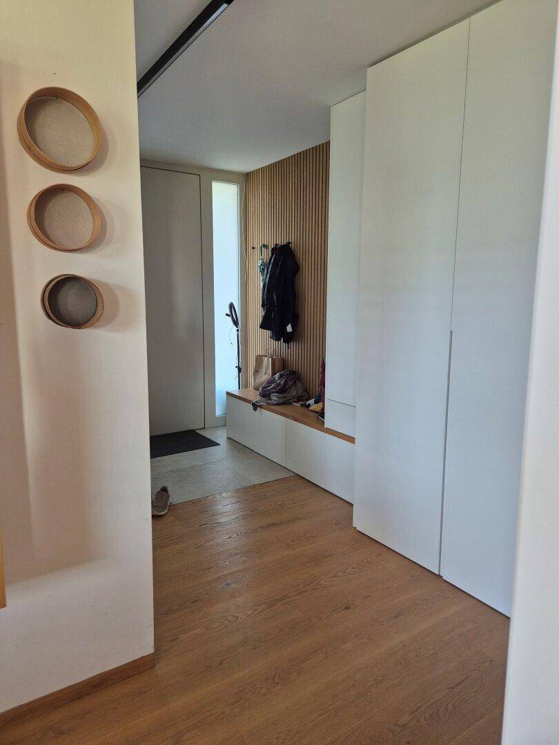 Eingangsbereich mit Holzboden, Garderobe und dekorativen Wandelementen.