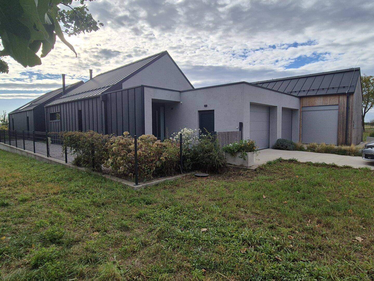 Modernes Haus mit Garage, grauer Fassade und gepflegtem Vorgartenbereich.