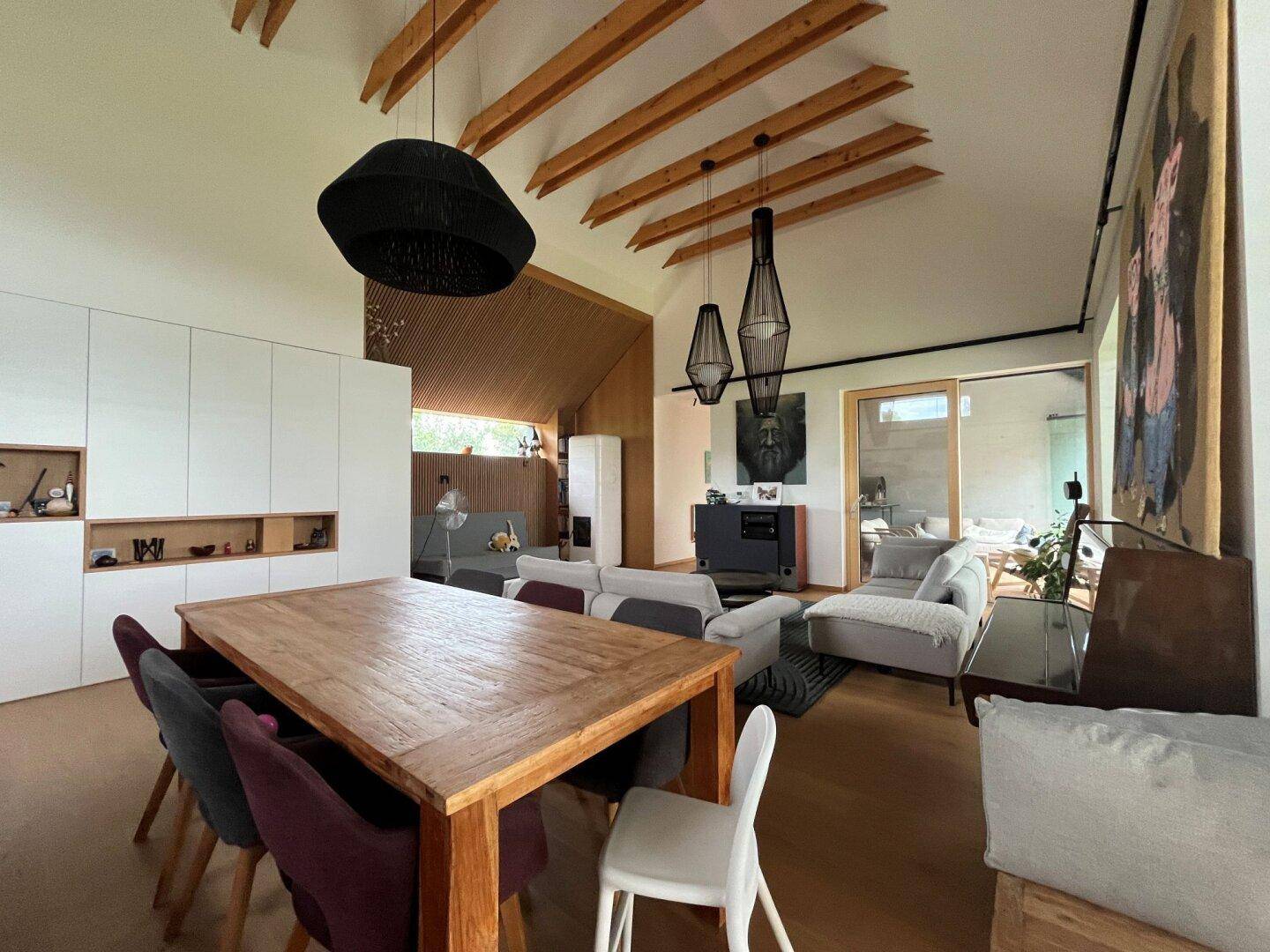 Essbereich mit großem Holztisch, modernen Stühlen und Blick in den Wohnbereich.