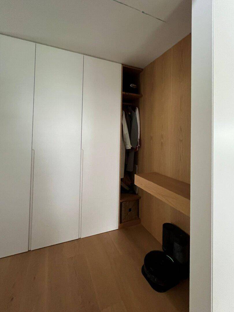 Moderner Flur mit Holzwandverkleidung und praktischen Einbauschränken für Kleidung.