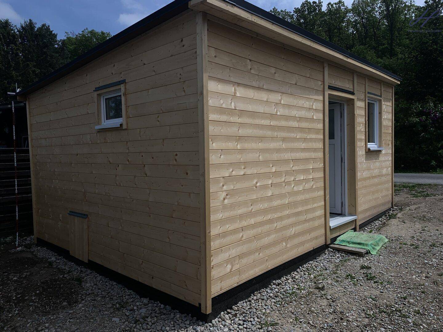 Seitenansicht des Holzhauses mit schlichter Holzverkleidung und einem kleinen Fenster.