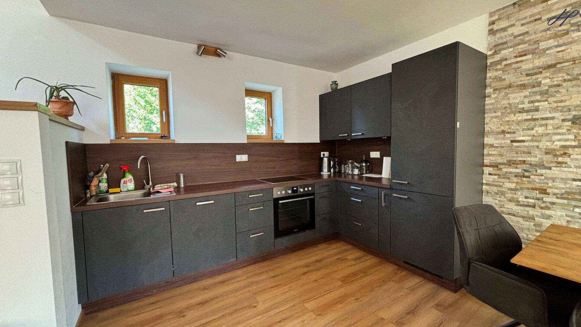 Moderne Küchenzeile in dunklem Grau mit integrierten Geräten und Holz-Arbeitsplatte.