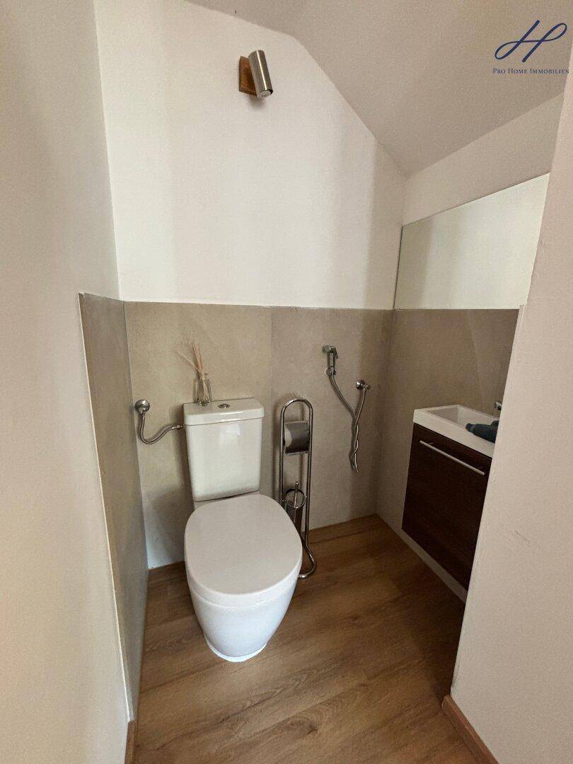 Kleines Gäste-WC mit modernem Wand-WC, Waschbecken und Holzboden.