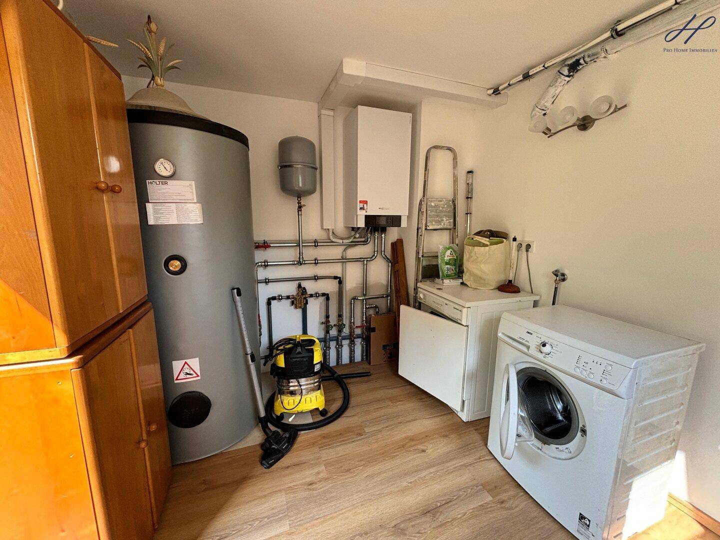 Technikraum mit Warmwasserspeicher, Heizungsanlage und Waschmaschine.