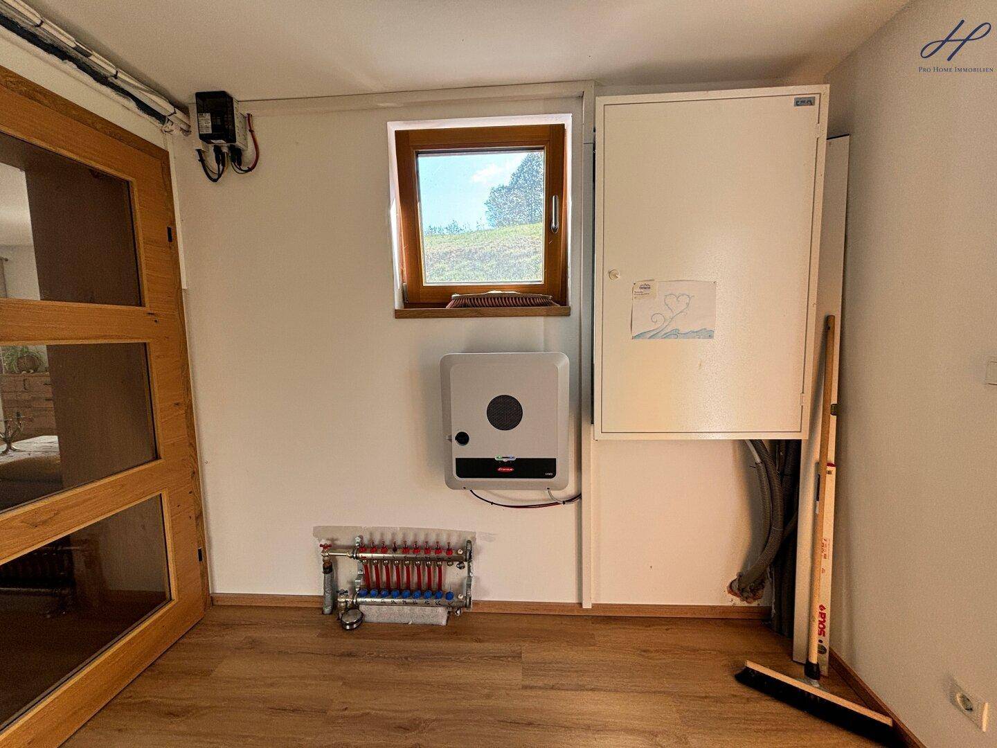 Technikraum mit Photovoltaik-Wechselrichter und Fußbodenheizungsverteiler.
