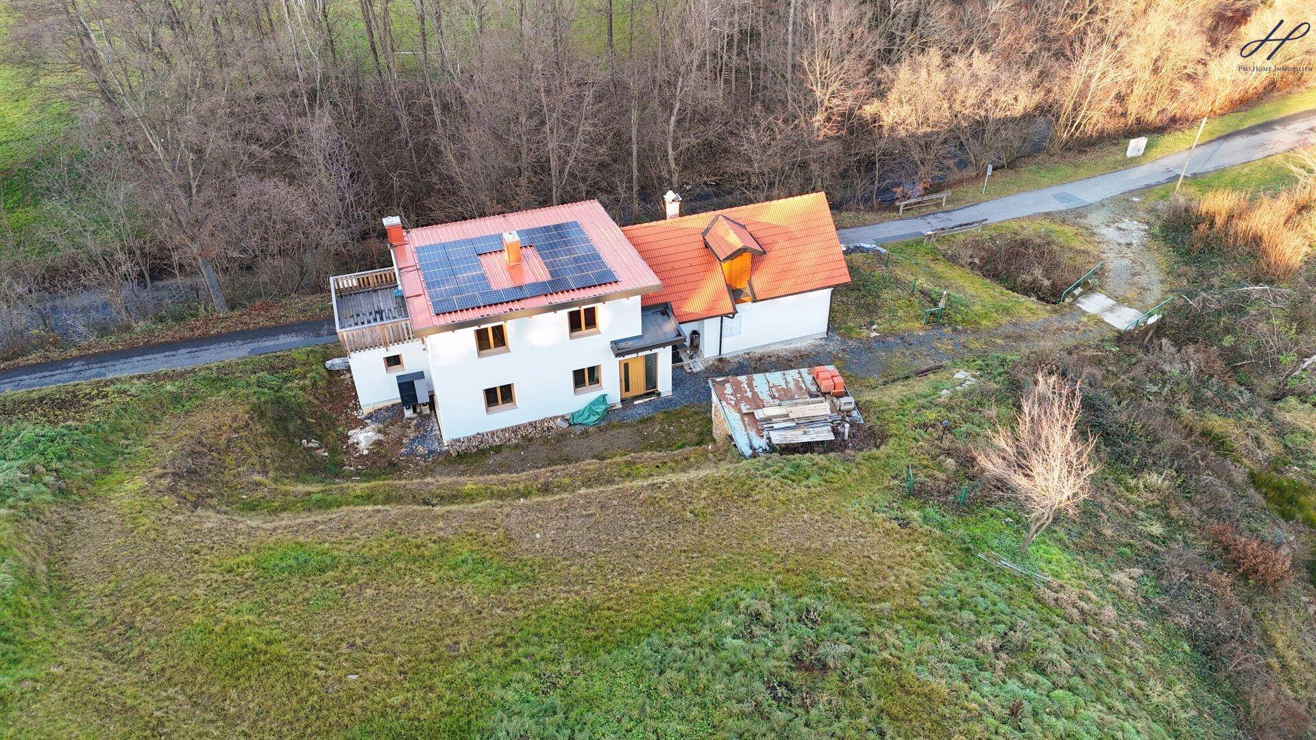 Luftaufnahme des Hauses mit Solaranlage auf dem Dach und angrenzendem weitläufigem Grundstück.
