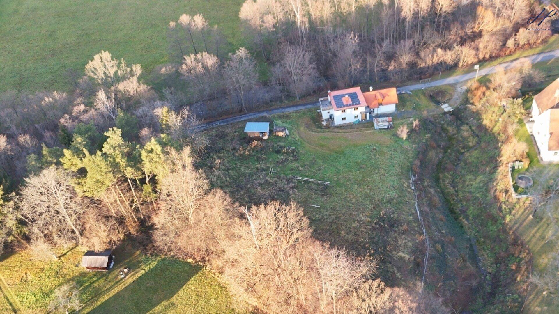 Weitläufige Luftaufnahme des Anwesens mit umliegenden Feldern und Wäldern in ländlicher Umgebung.