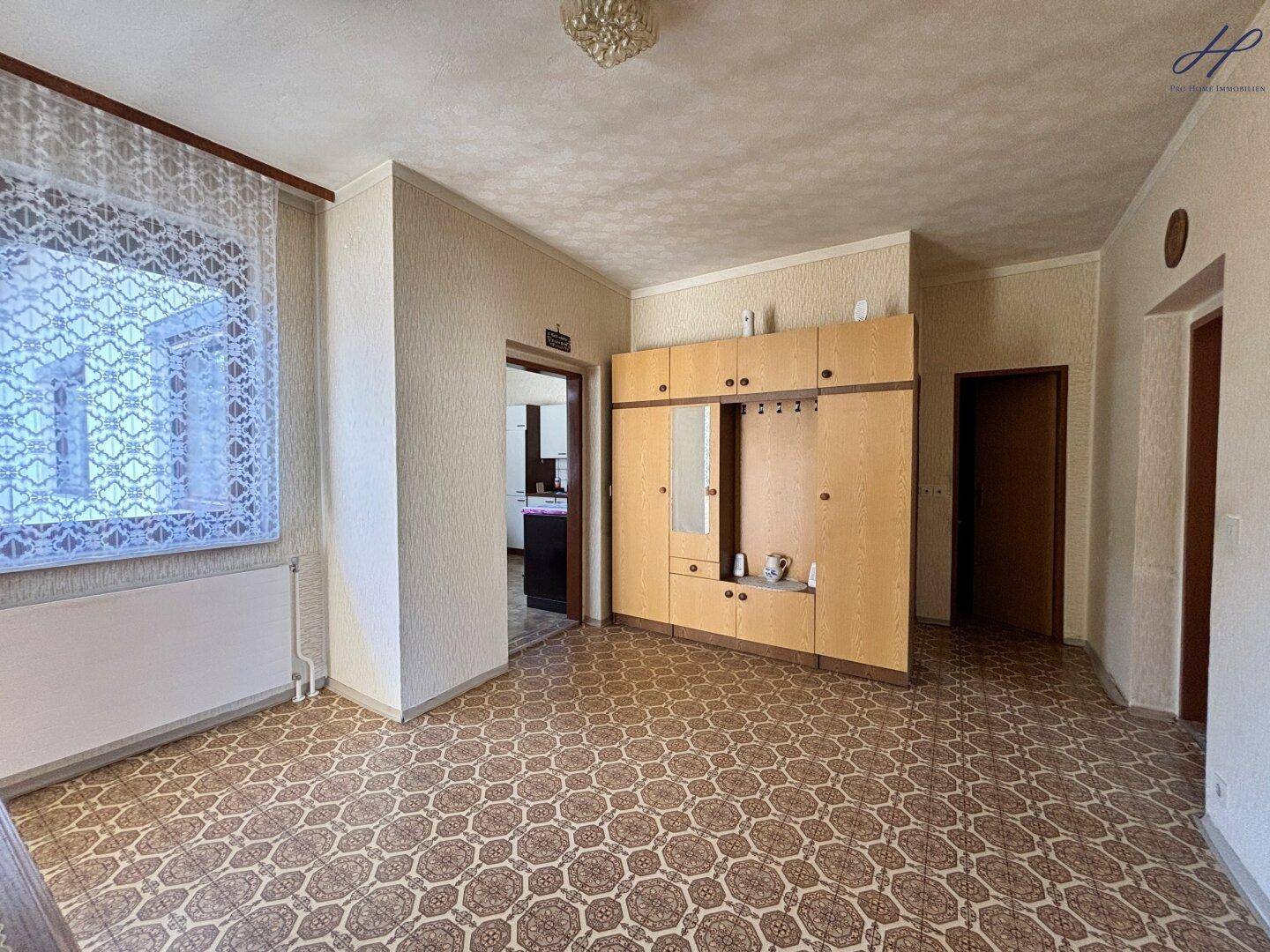 Eingangsbereich mit gemustertem PVC-Boden und einem großen Holzschrank.