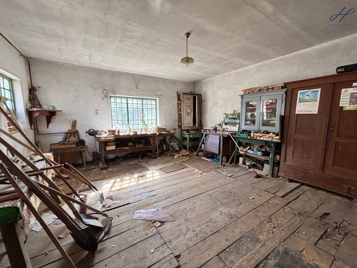 Geräumiger Werkstattraum mit Holzboden und verschiedenen Werkbänken.