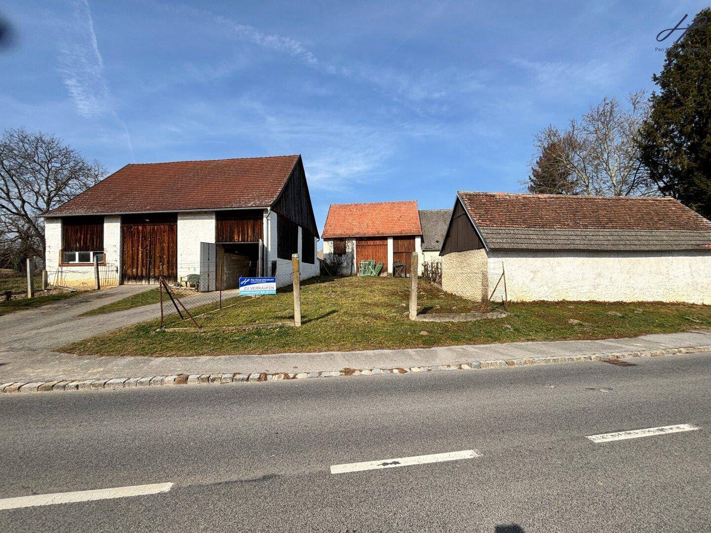 Gesamtansicht des Anwesens mit mehreren Gebäuden von der Straße aus.