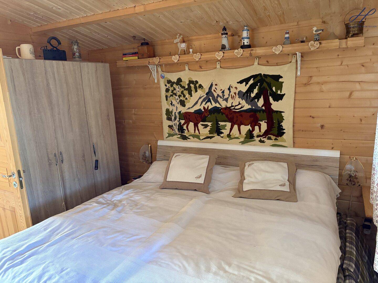 Gemütliches Schlafzimmer mit Holzwänden, Doppelbett und integriertem Kleiderschrank.