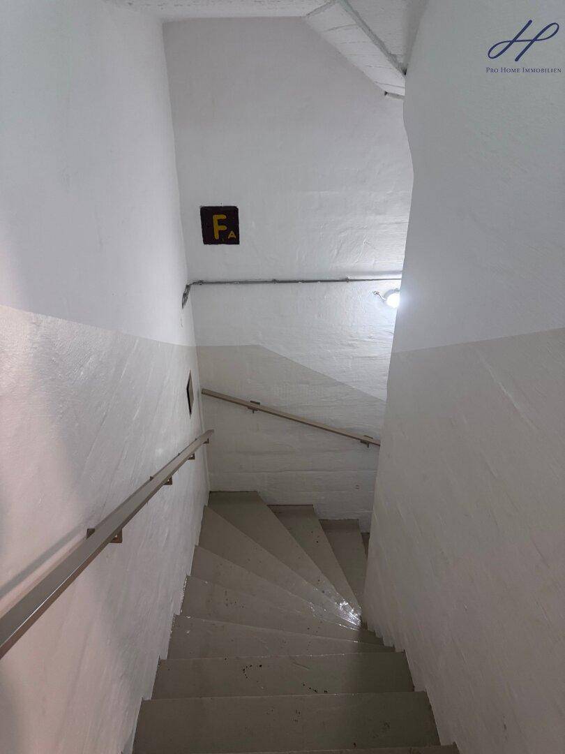 Treppenhaus mit schlichten Stufen und Handlauf, führt in die unteren Etagen.