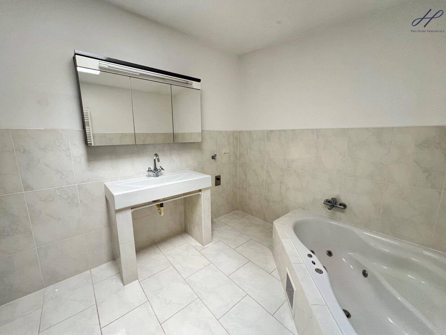 Geräumiges Badezimmer mit Whirlpool-Badewanne, modernem Waschtisch und Spiegelschrank.