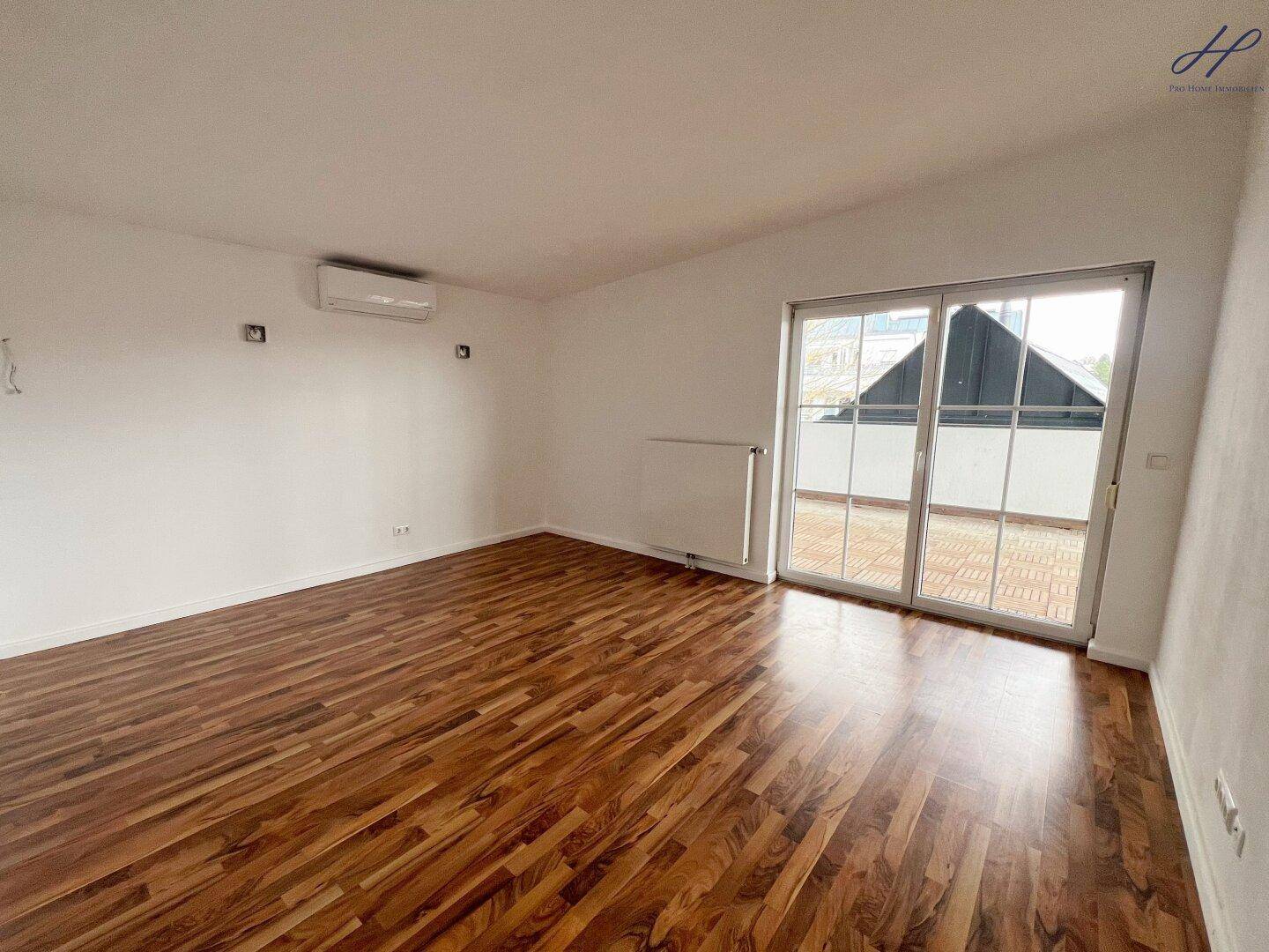 Schlafzimmer mit dunklem Holzboden, Klimaanlage und Zugang zur Außenterrasse.