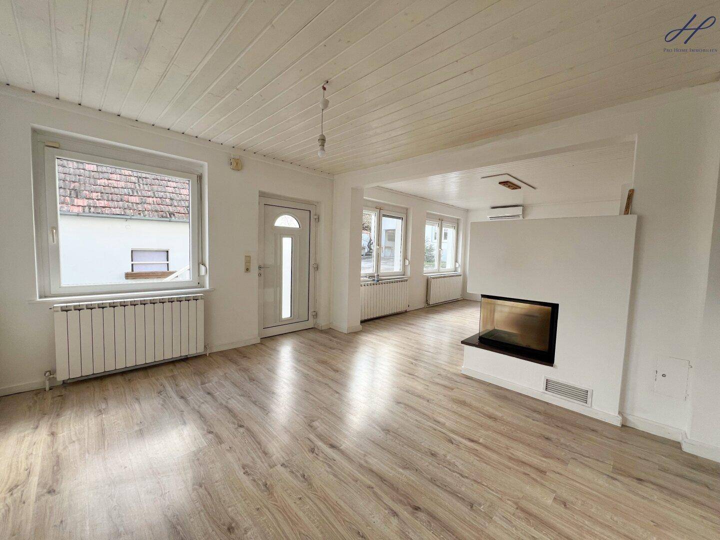 Helles Wohnzimmer mit Laminatboden, modernem Kamin und großen Fenstern für viel Tageslicht.