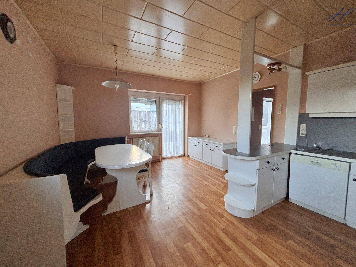 Geräumige Wohnküche mit Essbereich, Laminatboden und Zugang zum Außenbereich.