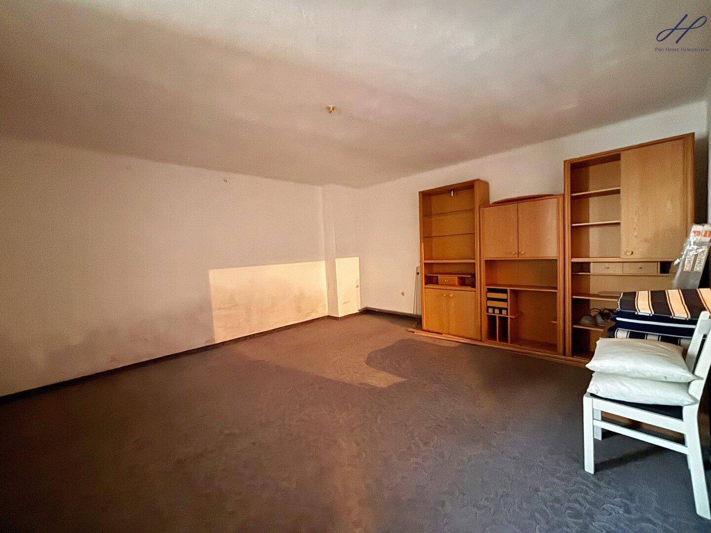 Geräumiger, leerer Raum mit Teppichboden und Einbauschränken, renovierungsbedürftig.