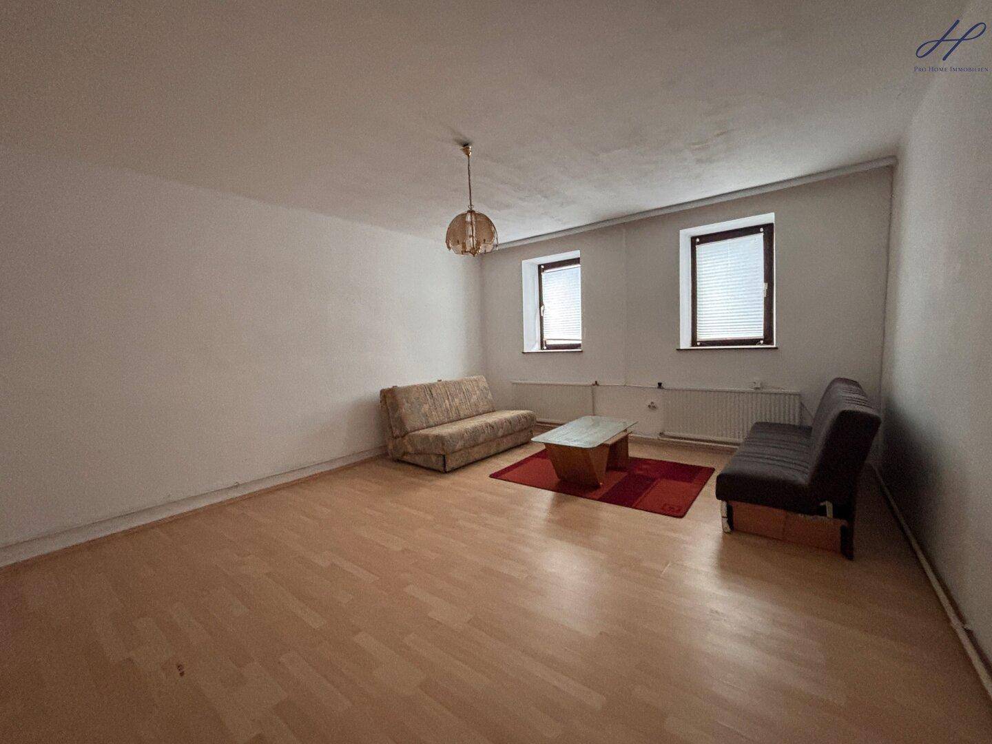 Wohnzimmer mit hellem Laminatboden, zwei Sofas und einem Couchtisch.