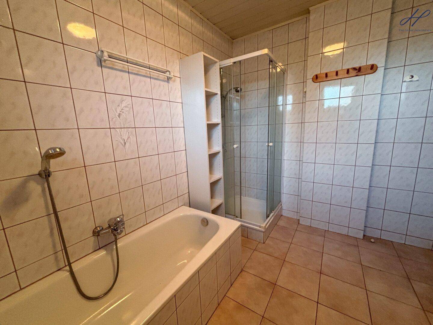 Badezimmer mit Badewanne und Duschkabine, komplett gefliest.