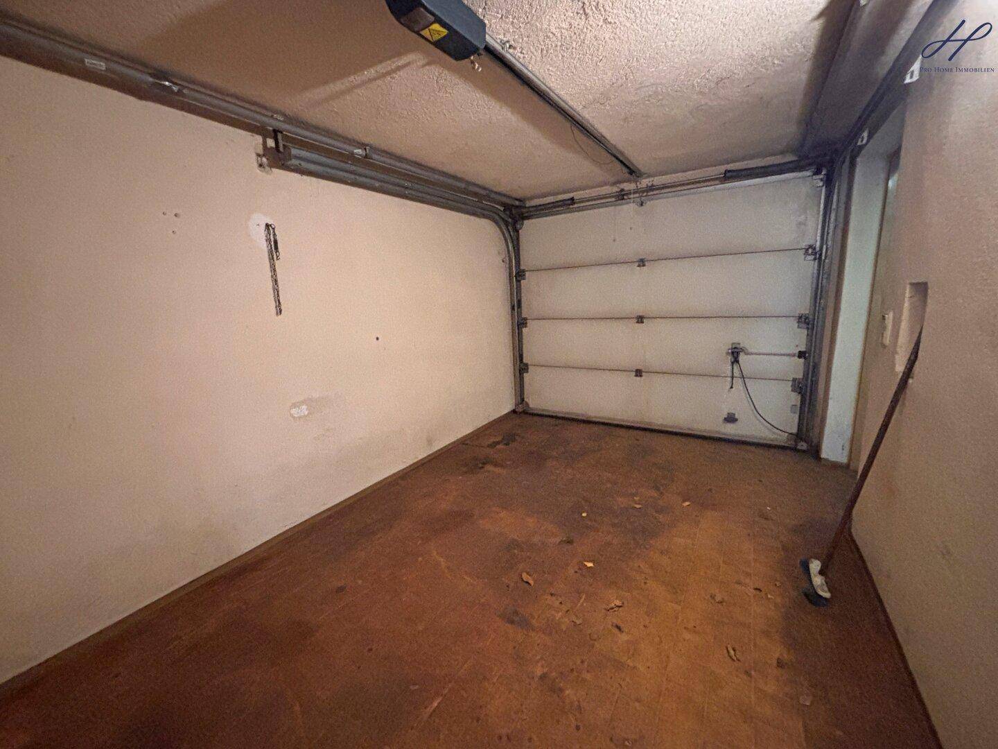 Innenansicht der Garage mit Garagentor und Betonboden.