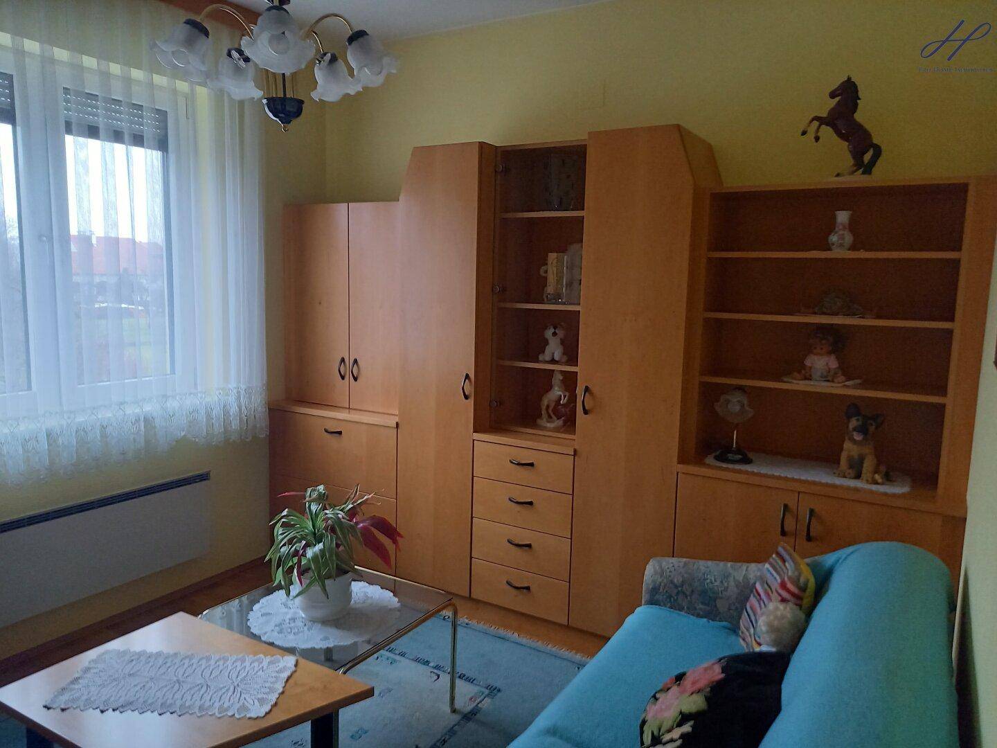 Gemütliches Wohnzimmer mit Sofa, Holzmöbeln und einem großen Fenster.