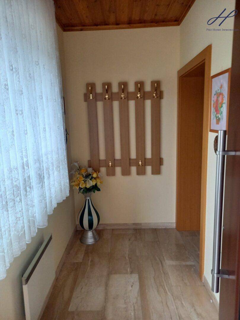 Eingangsbereich mit Garderobe, Holzdecke und hellem Fliesenboden.