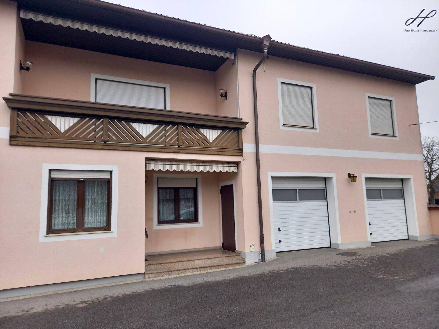 Vorderansicht des Hauses mit Balkon, Markise und zwei Garagen.