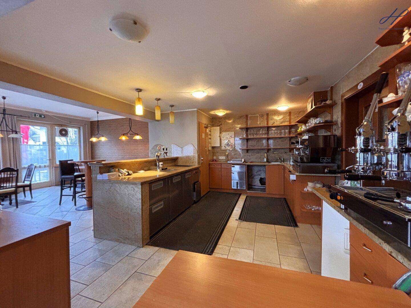 Professionelle Küche mit Edelstahlgeräten, Arbeitsflächen und Regalen, ideal für Gastronomiebetriebe.