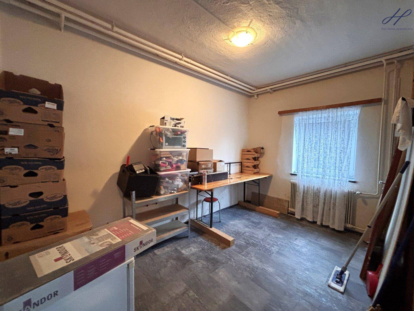 Praktischer Abstellraum mit Fenster, Heizung und Regalen, ausgestattet mit robustem Laminatboden.