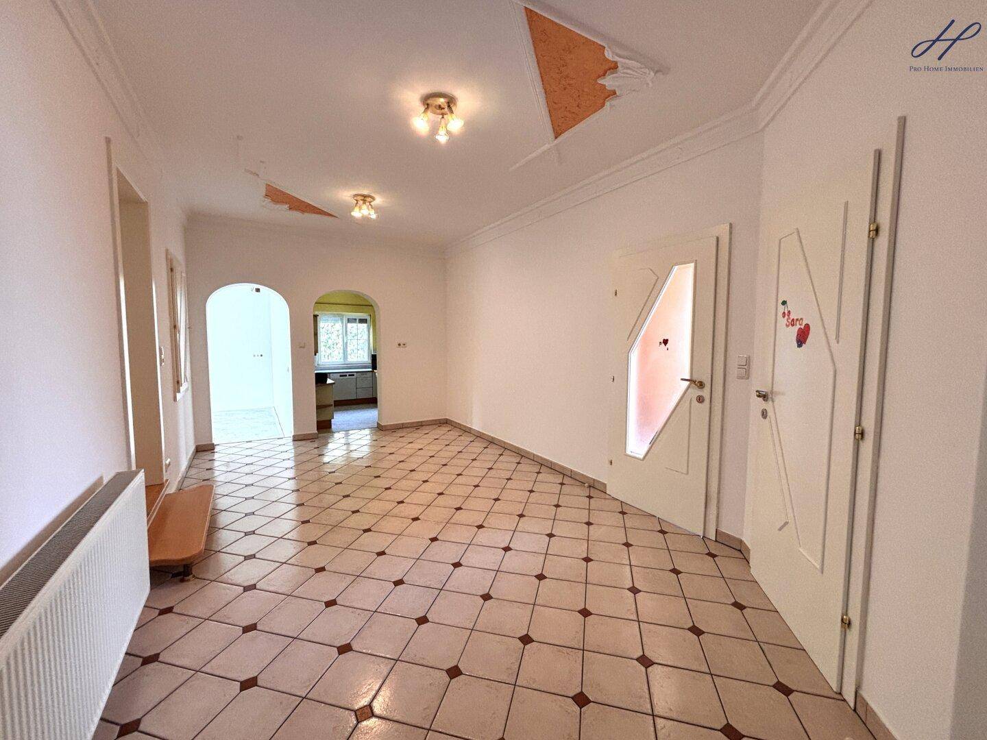 Geräumiger Flur mit Fliesenboden und Blick in den hinteren Bereich des Hauses.