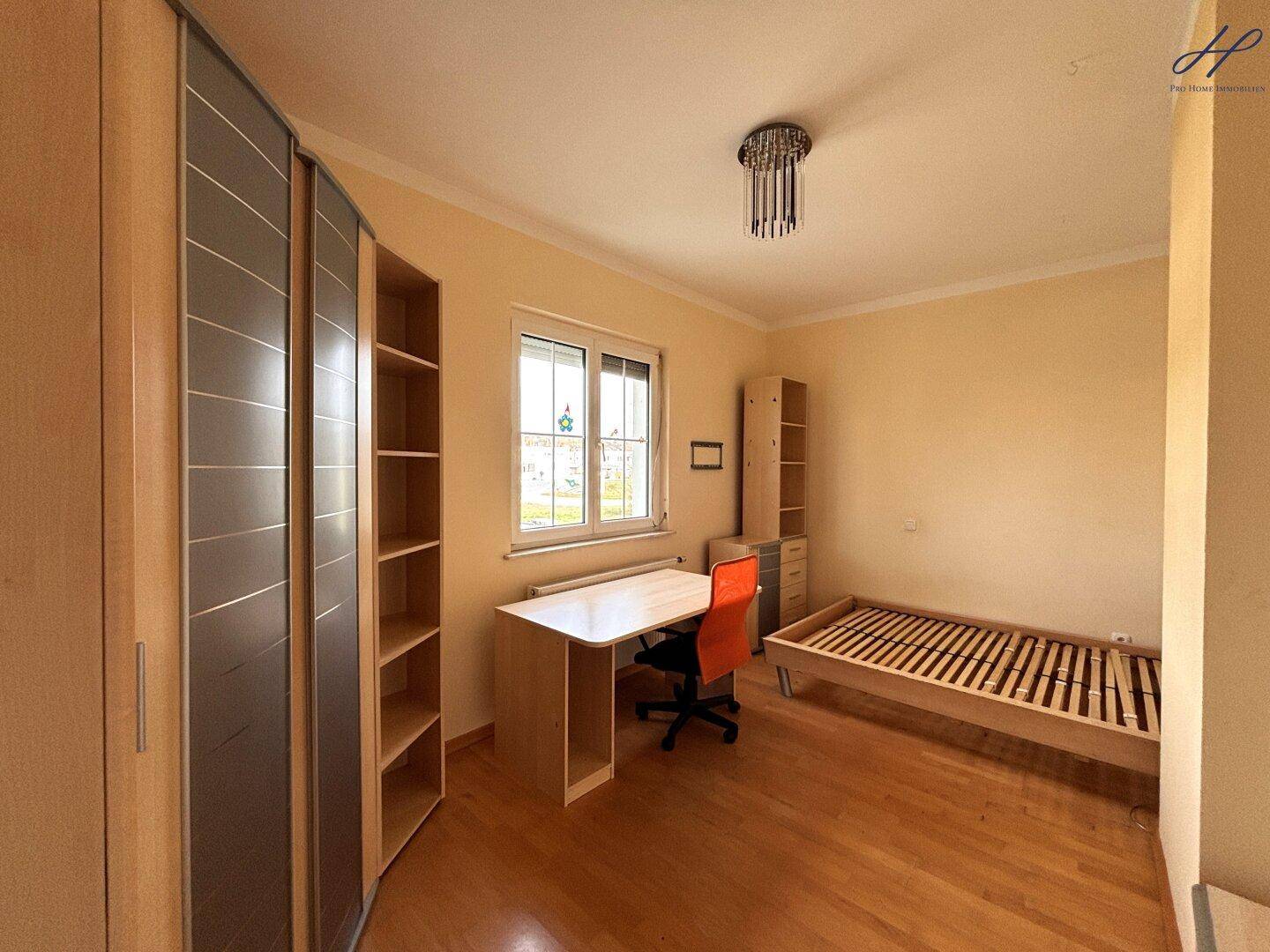 Schlafzimmer oder Büro mit Holzparkettboden, Schrank und Schreibtisch.