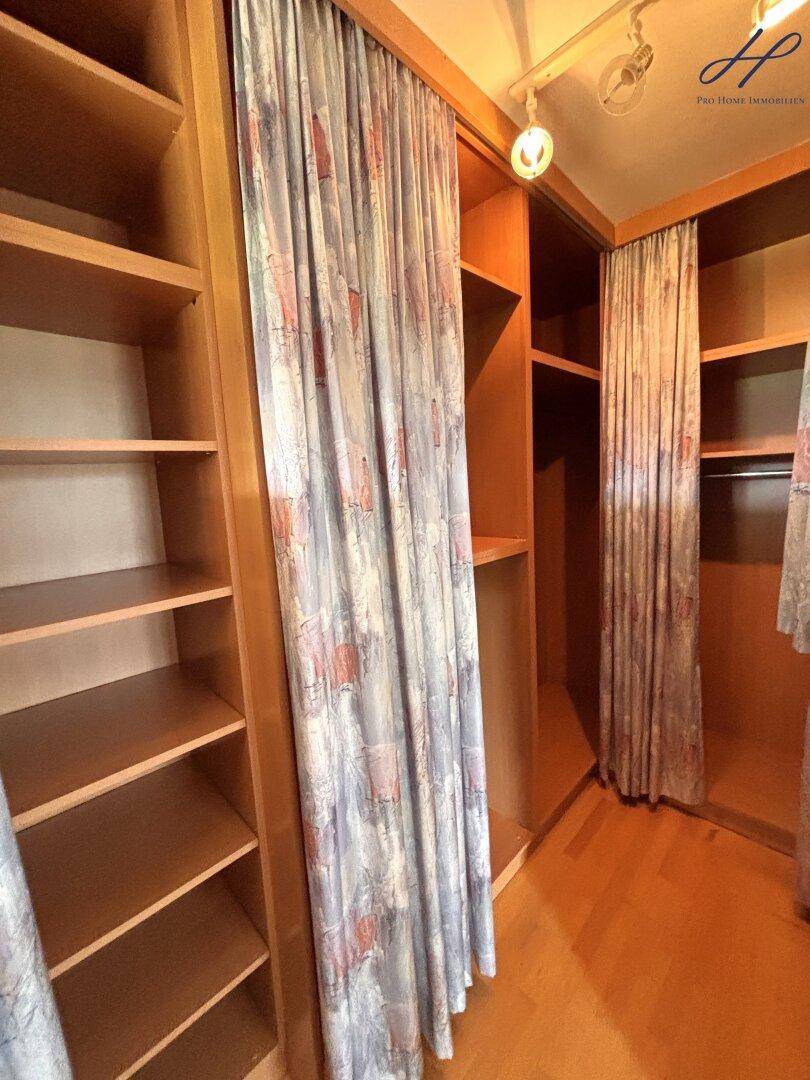 Praktischer begehbarer Kleiderschrank mit vielen Regalen und Vorhängen.