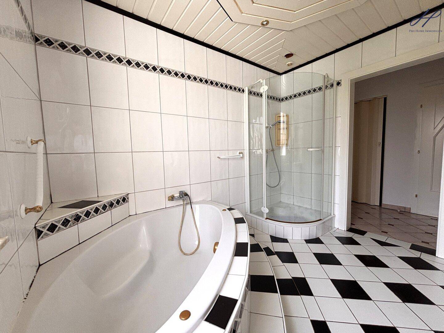 Badezimmer mit Eckbadewanne, Duschkabine und schwarz-weißem Fliesenboden.