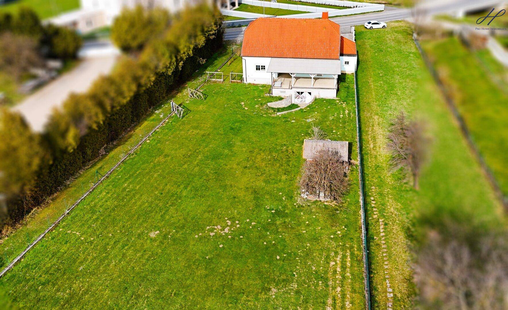 Weitläufiger grüner Gartenbereich hinter dem Haus mit viel Platz und einem kleinen Schuppen.