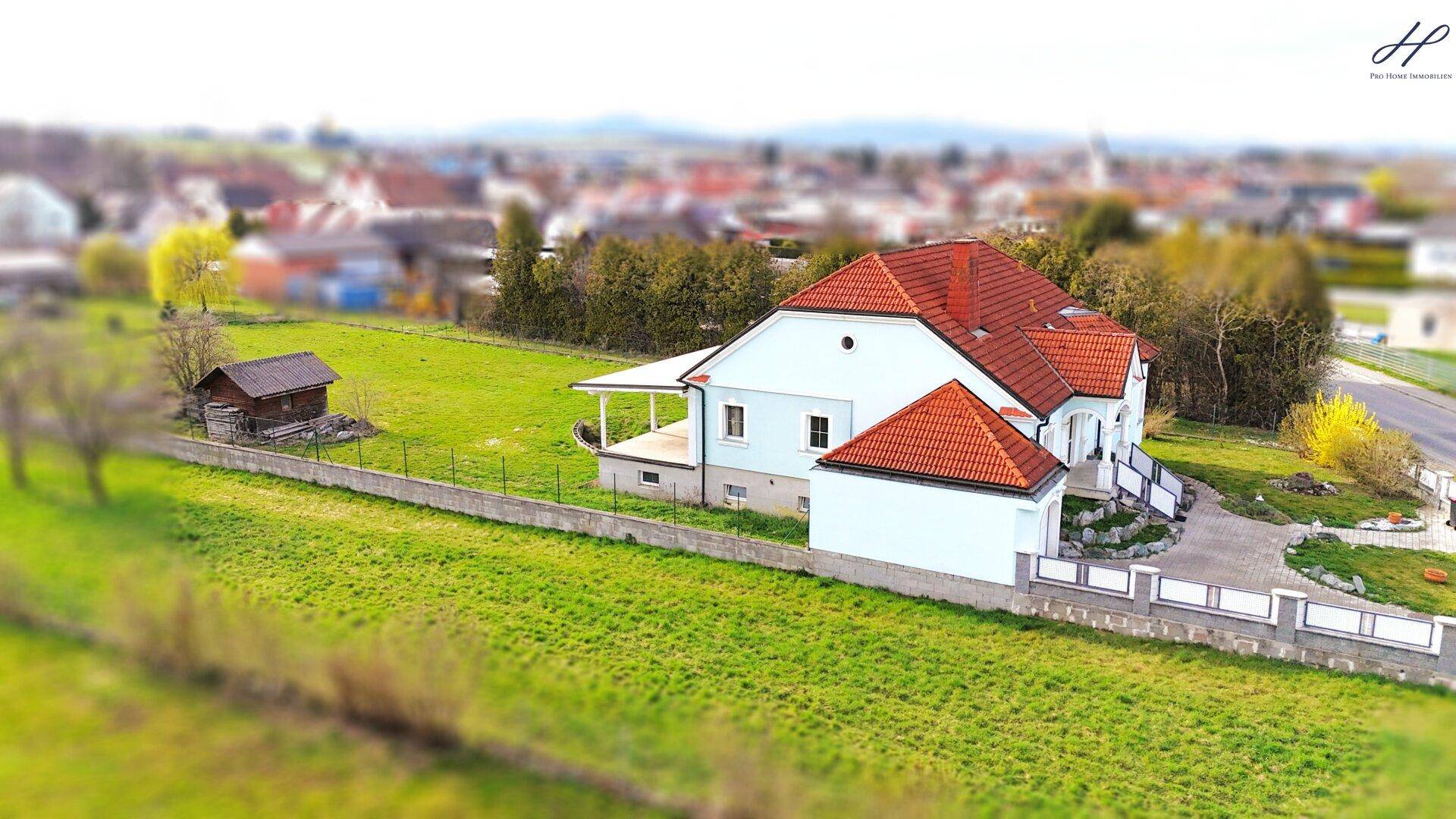 Seitenansicht des Hauses mit überdachter Terrasse und weitläufigem grünen Grundstück in ruhiger Lage.