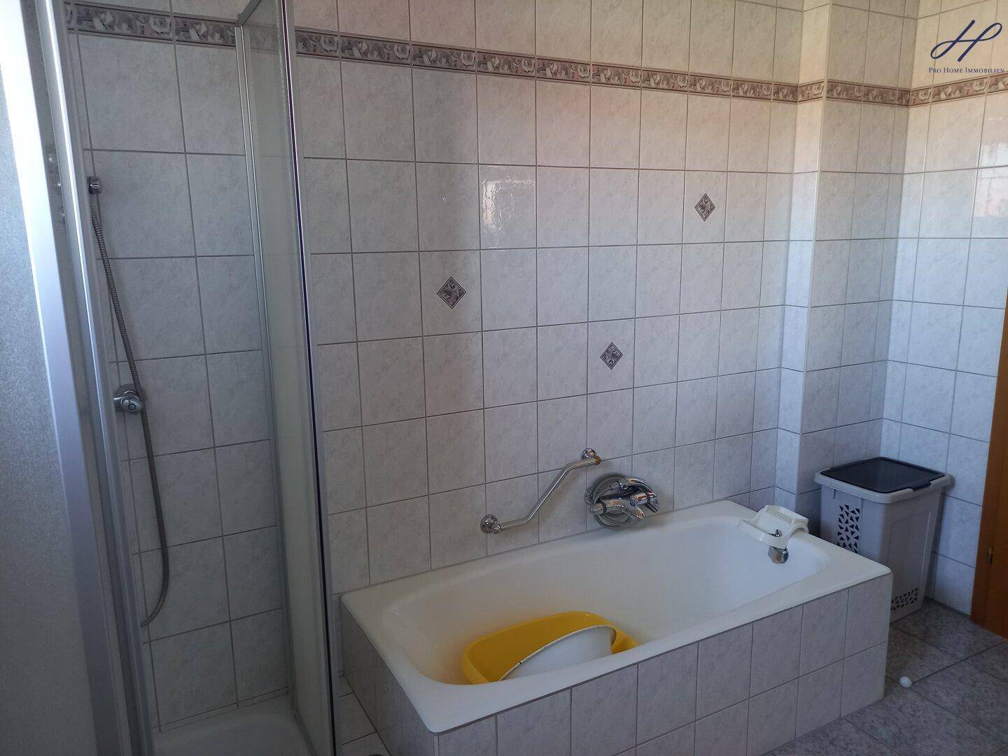 Badezimmer mit Badewanne, Duschkabine und hellen Fliesen.