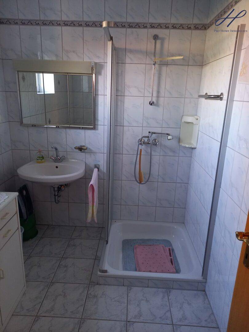 Badezimmer mit Duschkabine, Waschbecken und Spiegelschrank.