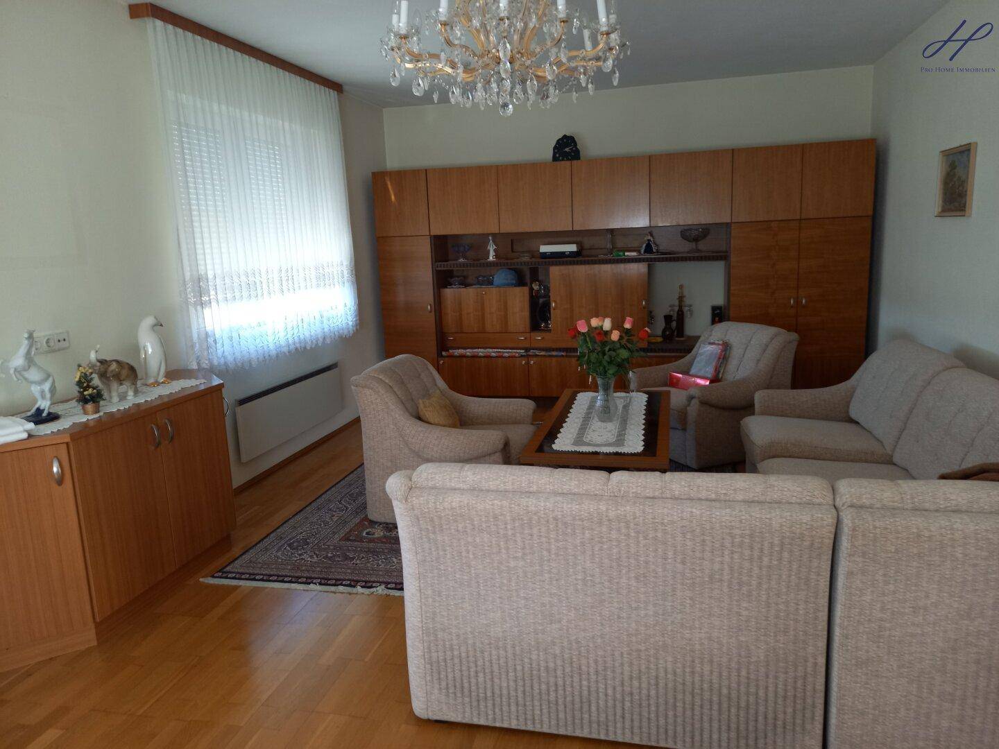 Geräumiges Wohnzimmer mit Parkettboden, bequemen Sofas und einem Kronleuchter.