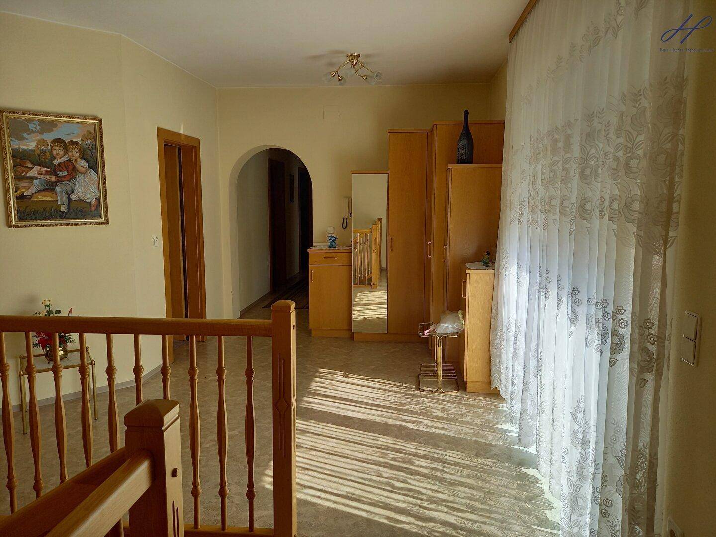 Heller Flur im Obergeschoss mit Holzmöbeln und viel natürlichem Licht.