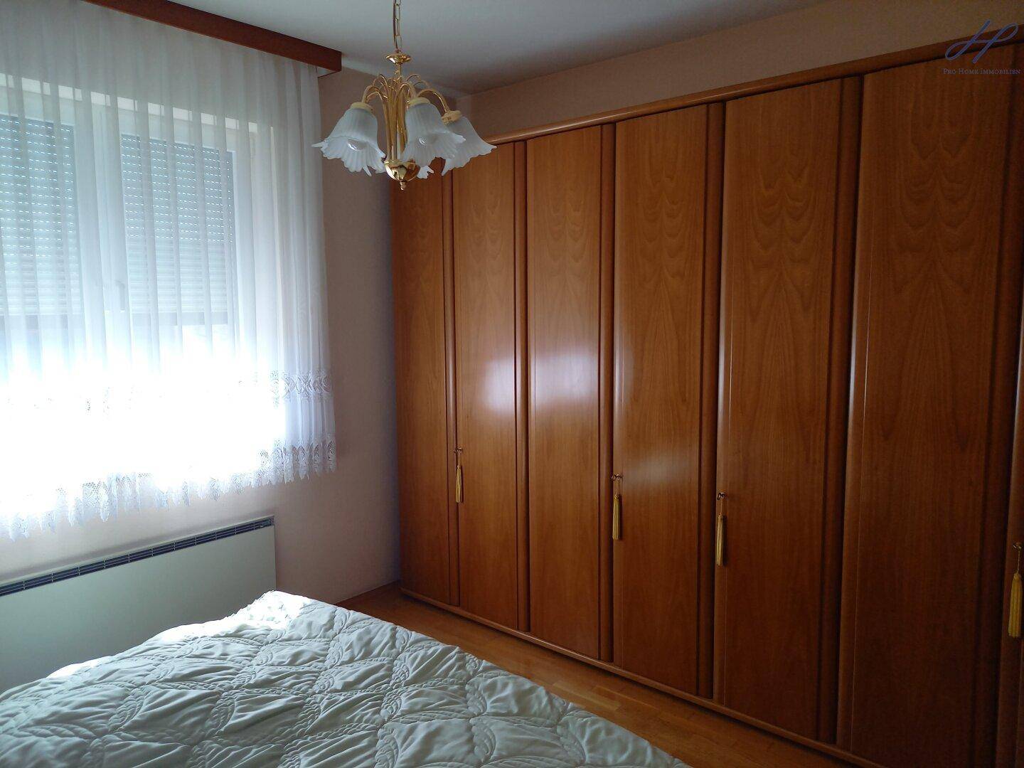 Schlafzimmer mit großem Einbauschrank, Doppelbett und hellem Fenster.