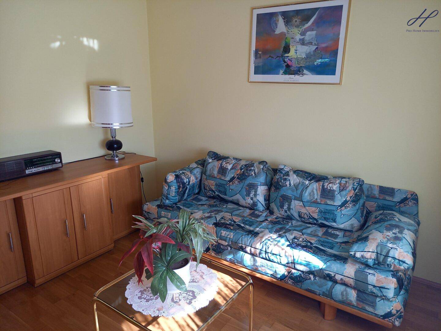 Gemütliches Wohnzimmer mit Sofa, Holzmöbeln und einem kleinen Couchtisch.