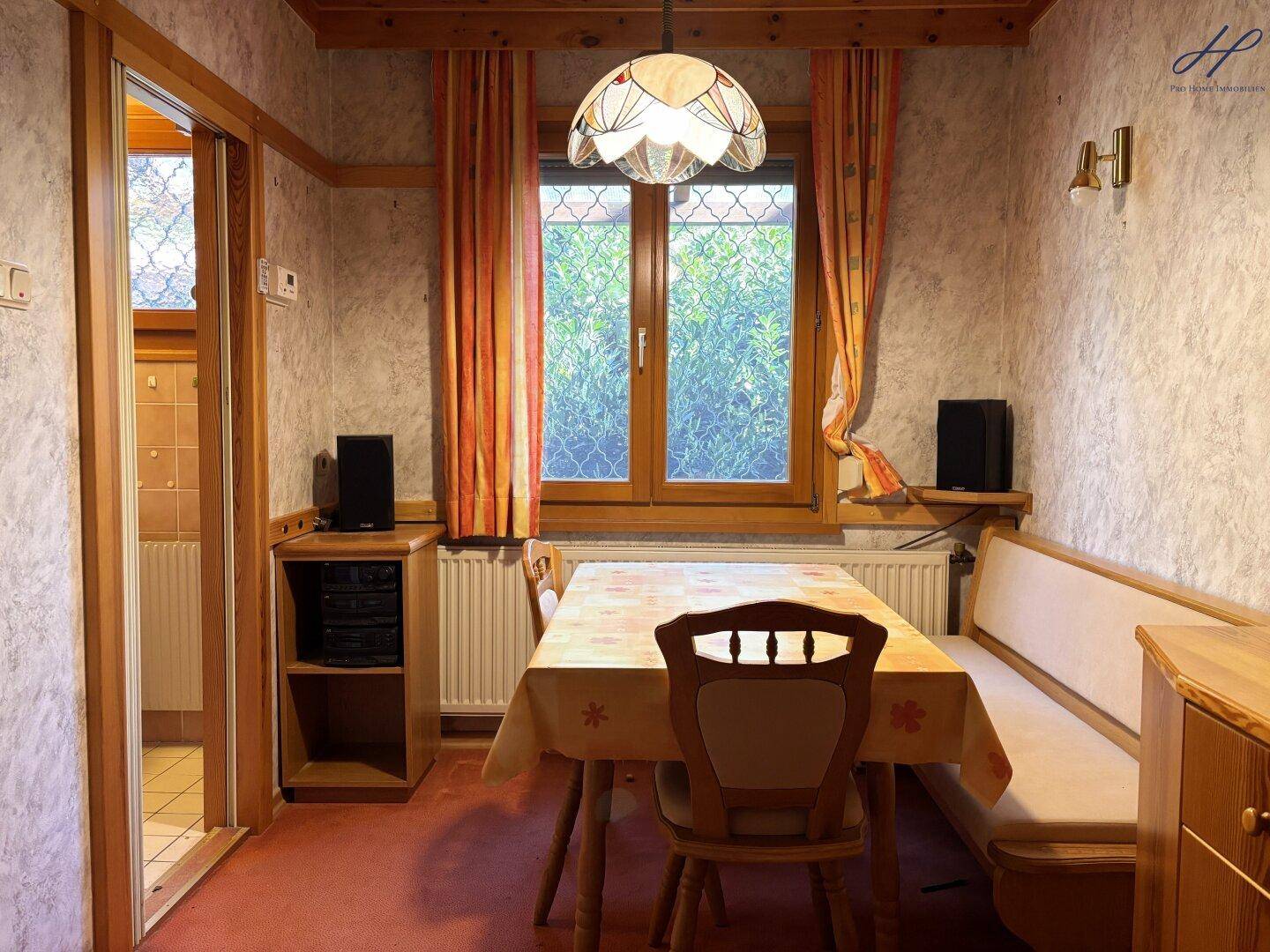 Essbereich mit Holztisch, Sitzbank und Fenster mit Blick ins Grüne.