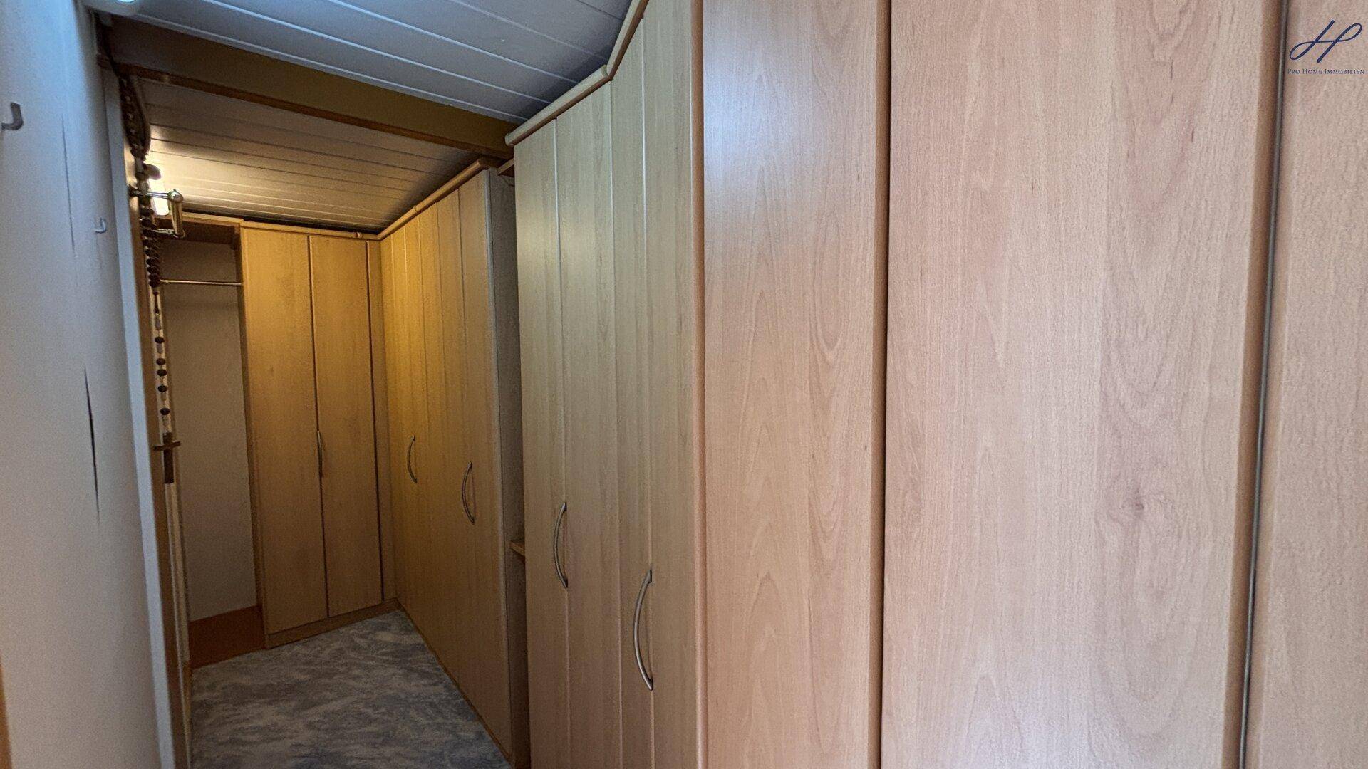 Geräumiger begehbarer Kleiderschrank mit vielen Holzschränken und Stauraum.