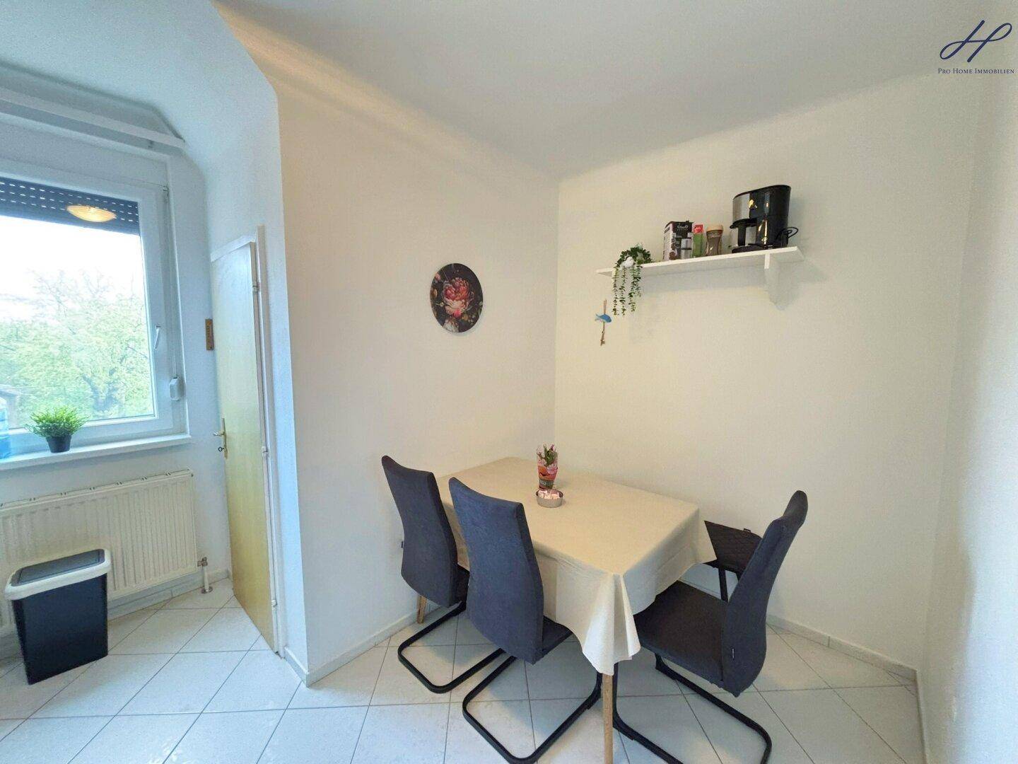 Gemütlicher Essbereich mit Tisch und Stühlen neben einem Fenster, ideal für Mahlzeiten in der Küche.