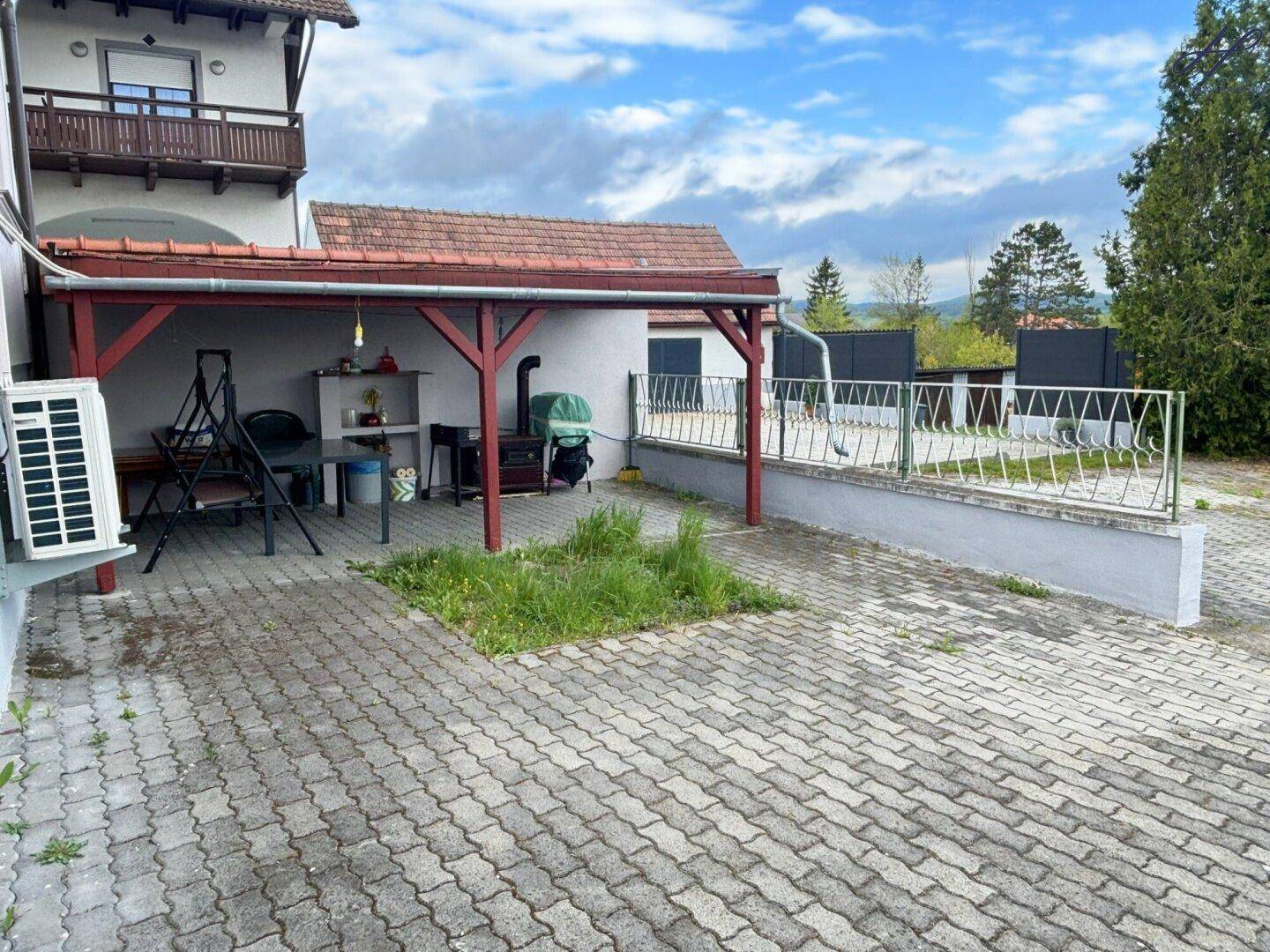 Überdachte Terrasse mit gepflastertem Bereich und Sitzgelegenheiten, ideal für entspannte Stunden im Freien.