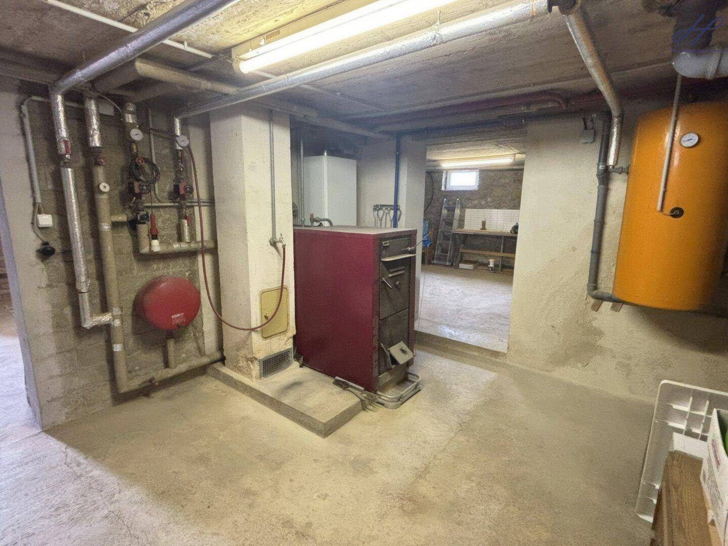 Heizungsraum im Keller mit Kessel und Warmwasserspeicher, gut zugänglich für Wartungsarbeiten.